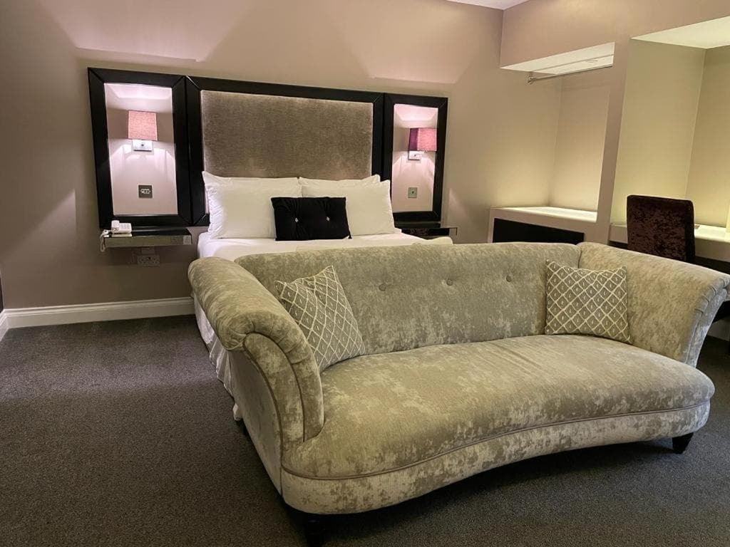 Luxury suite with green velvet chaise longue and upholstered king bed
