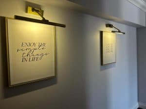Hotel corridor with framed inspirational prints lit by picture lights
