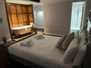 Suite with king bed and freestanding bath visible through en-suite door